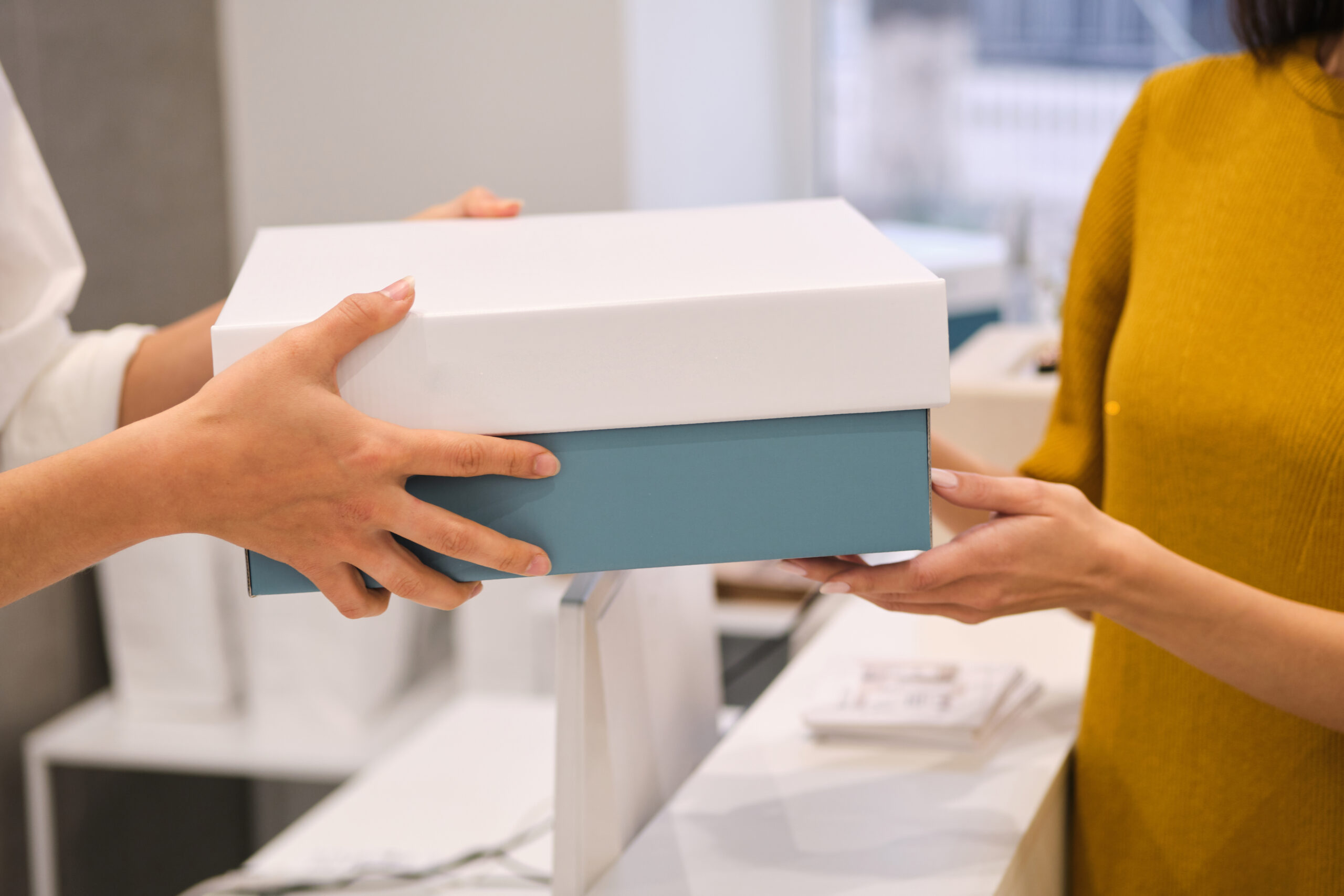 Close up fashion consultant giving packing clothes to customer in modern store