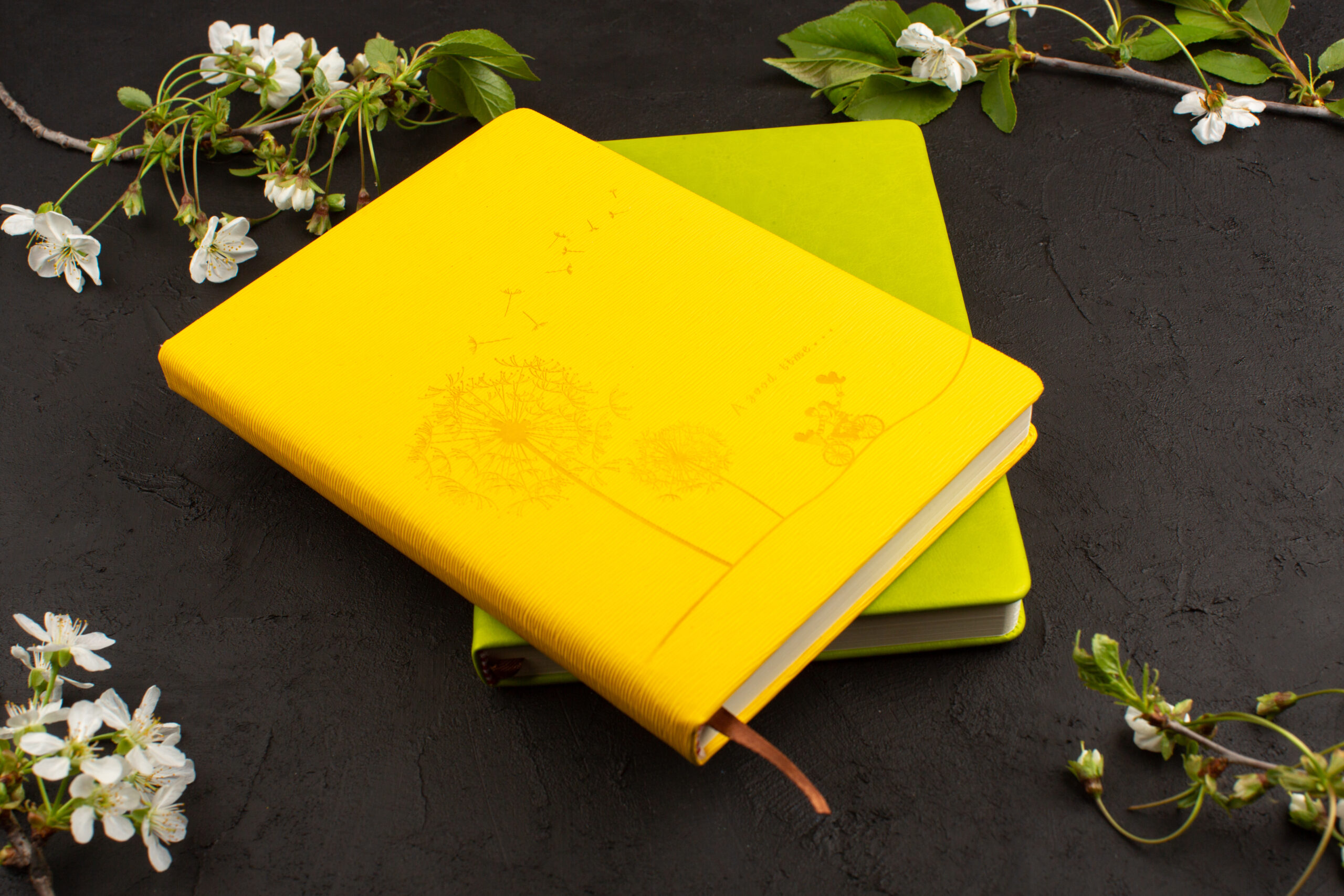 top-view-yellow-green-copybooks-along-with-white-flowers-dark-background