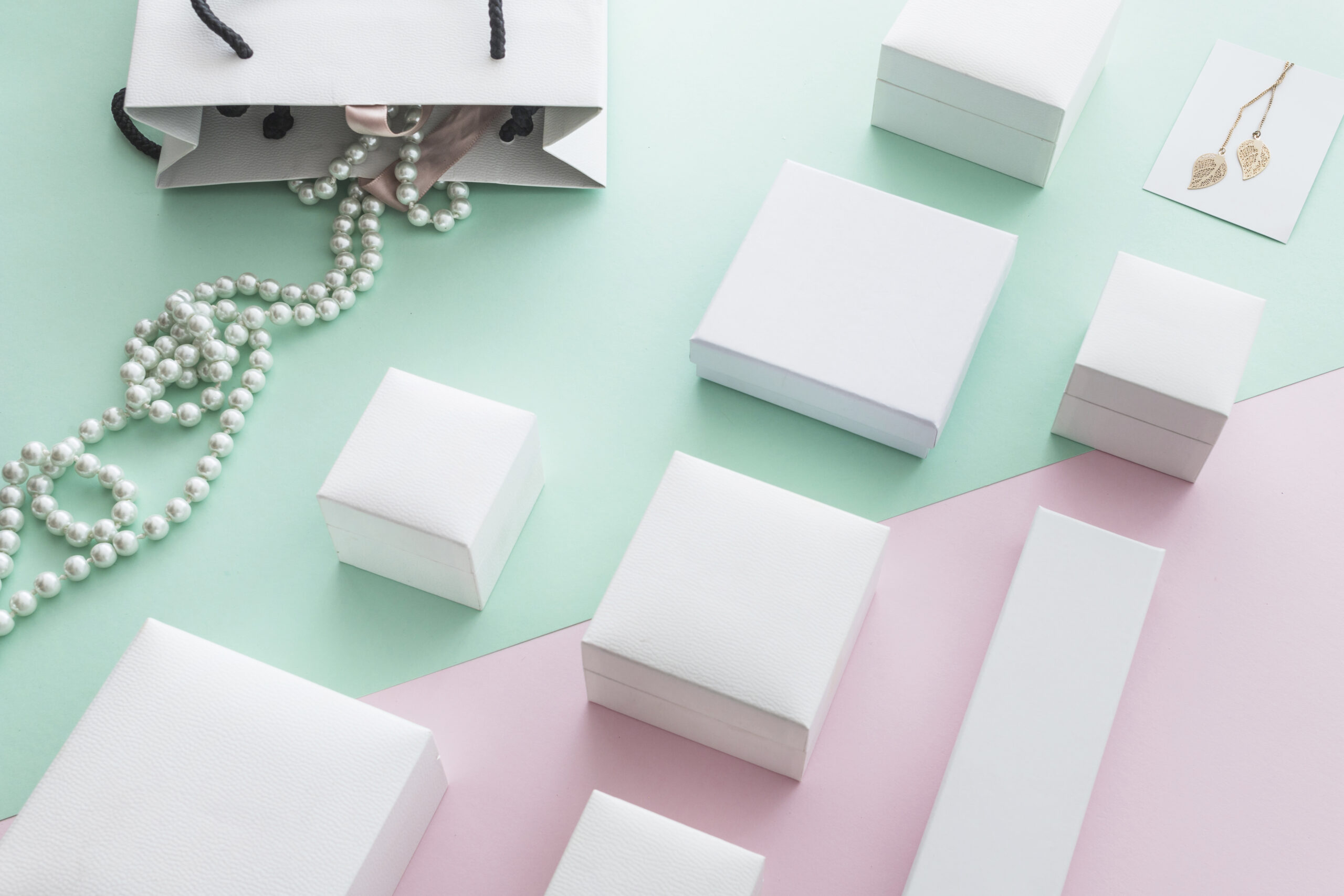 white-pearls-necklace-with-different-white-boxes-pastel-paper-background