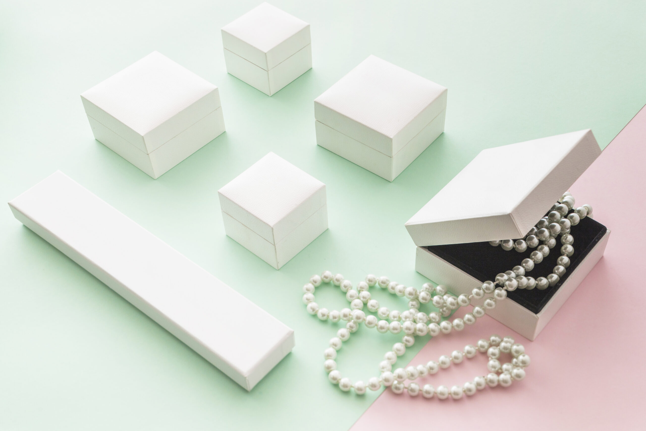 white-pearls-necklace-with-white-boxes-pink-green-pastel-backdrop